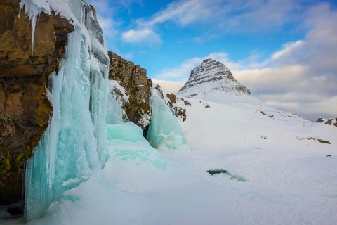 Frozen waterfall Kirkjufellsfoss and the mountain Kirkjufell with snow
