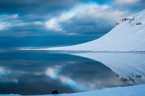 Snow-covered coastal landscape with water reflection