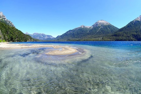 Lake with crystal clear water in front of mountain landscape