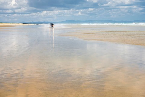 Black Hyundai Santa Fe 4x4 off-road vehicle drives on the sandy beach of Ninety Mile Beach in the water