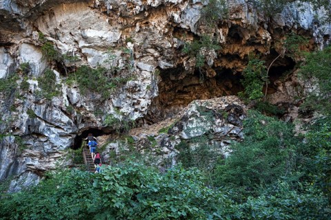 Tourists climbing into a cave in a karst cone called mogote