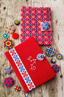 Two Posamentenknopf clasps for two red diaries and a selection of Posamentenknopfen on wooden panel