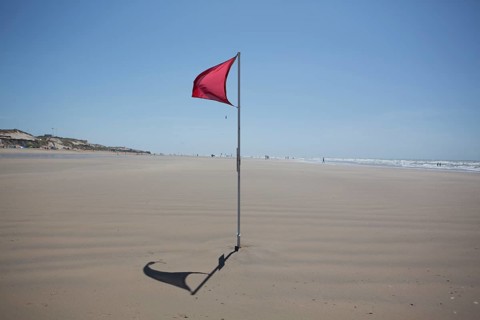 Red flag on the beach warn against dangerous drifts