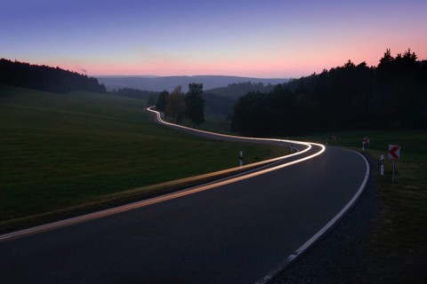Car driving on winding country road in the evening