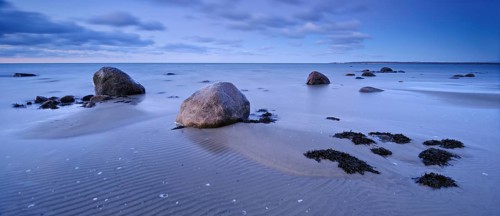 Sandy beach beach with large boulders and seaweed