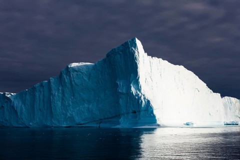Iceberg under dark cloud sky