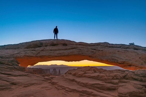 Young man standing on rock arch