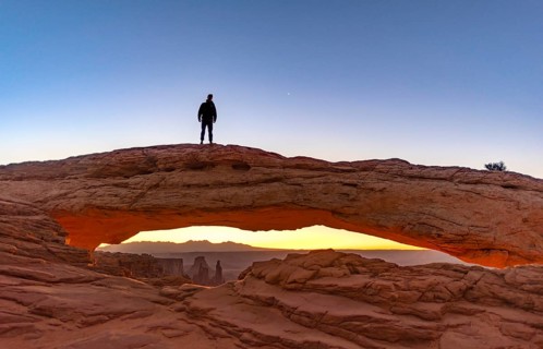 Young man standing on rock arch