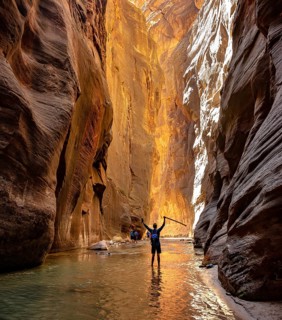 Hiker walks in the water and stretches arms into the air