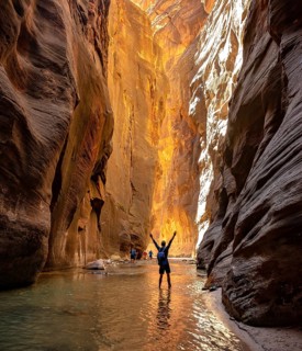 Hiker walks in the water and stretches arms into the air
