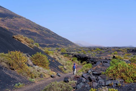 Woman walks on hiking trail through lava field