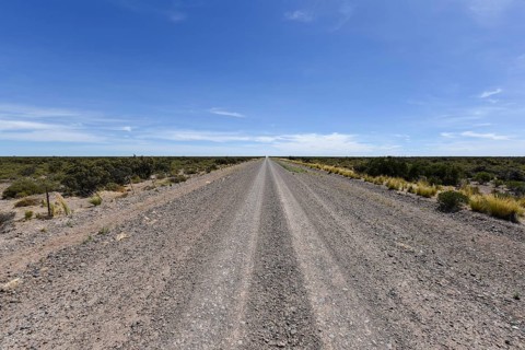 Long straight gravel road through the Pampa to the horizon