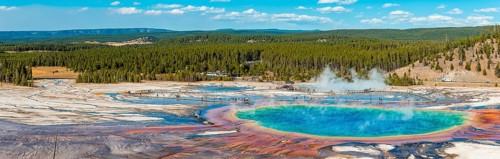 Visitors on footbridge over steaming hot spring with coloured mineral deposits