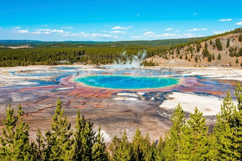 Visitors on footbridge over steaming hot spring with coloured mineral deposits
