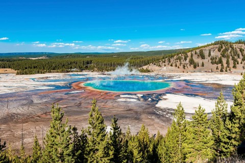 Visitors on footbridge over steaming hot spring with coloured mineral deposits