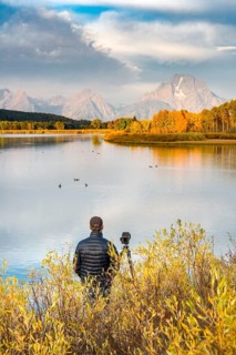Photographer standing with tripod at the river