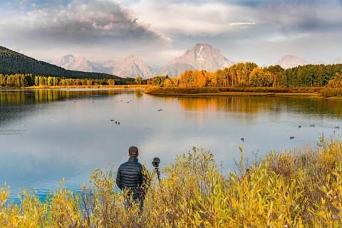 Photographer standing with tripod at the river