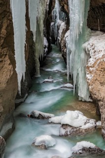 Path to Partnach wild river in the Partnach gorge with long icicles and snow in winter