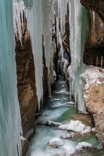 Path to Partnach wild river in the Partnach gorge with long icicles and snow in winter