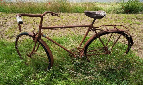 Rusted bicycle in grass by roadside