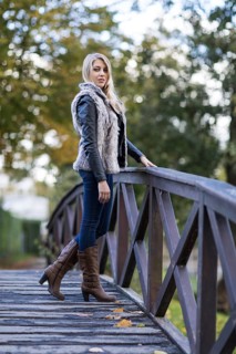 Young blonde woman poses on a wooden bridge