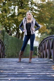Young blonde woman poses confidently on a wooden bridge