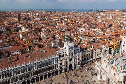 Procuratie Vecchie building with St Mark's clock tower and St Mark's Basilica and old architectural style residential buildings with terracotta rooftops taken from the Campanile bell tower in St Mark'...