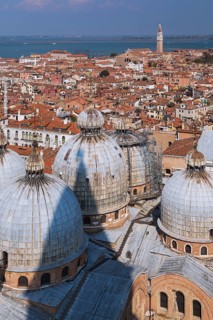 St Mark's Basilica with Romanesque domes and ornate Gothic and Byzantine architectural details plus old Renaissance architectural style residential buildings with terracotta rooftops and lagoon