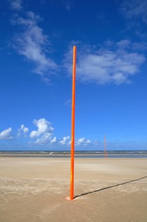 Orange-red marker posts on the beach