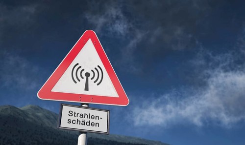Warning sign against blue sky with clouds