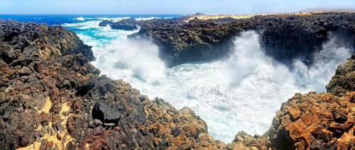 Surf on black basalt cliffs