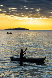 Man in a little fishing boat at sunset