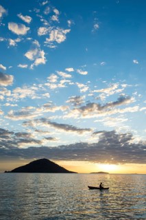 Man in a little fishing boat at sunset
