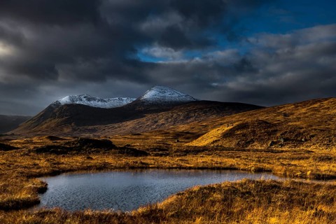 Small lake in the foreground snow-covered mountain peaks of Meall aÂ´Bhuiridh and Clach Leathad in the background and dramatic clouds