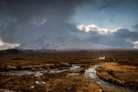 Waterfall of AltDearg Mor with snowy peaks of Marsco and Sgurr Nan Gillean and small house