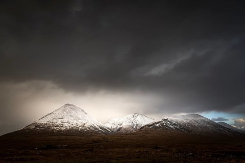 Moor landscape with snow-covered peaks of the Cullins Mountains in front of dramatic clouds in Highland Landscape