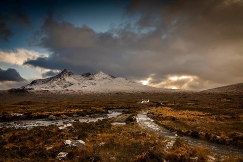 Waterfall of AltDearg Mor with snowy peaks of Marsco and Sgurr Nan Gillean and small house