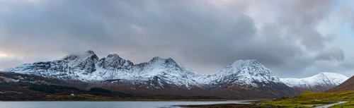 Loch Slapin with small house in Highland landscape with snowy Cullin mountains in the background