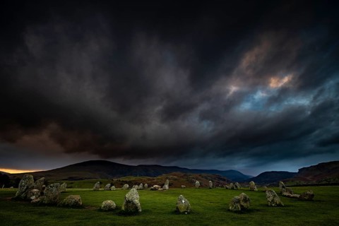 Stone circle with dramatic dark cloud sky