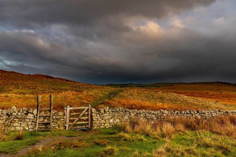 Stone wall in autumn landscape with dark sky