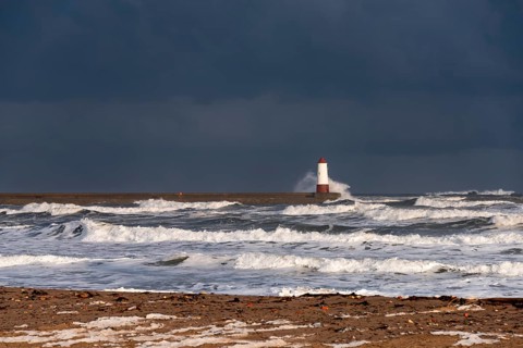 Berwick Lighthouse with strong surf and dark cloudy sky