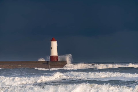Berwick Lighthouse with strong surf and dark cloudy sky