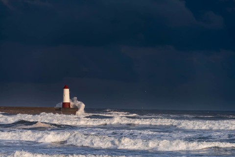 Berwick Lighthouse with strong surf and dark cloudy sky