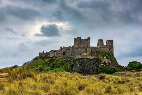 Dune landscape with Bamburgh Castle under a cloudy sky