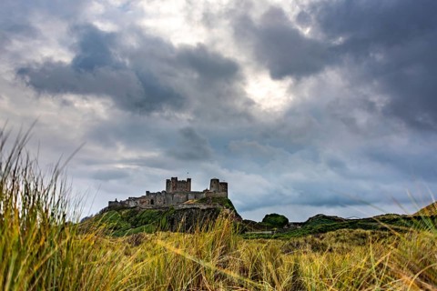 Dune landscape with Bamburgh Castle under a cloudy sky