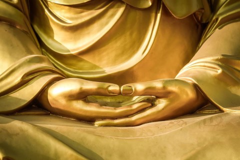 Hands of a Buddha sculpture in meditation posture