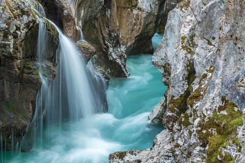 Emerald green wild river Soca flows through narrow canyon