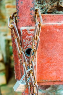 Padlock with iron chain hanging on a door