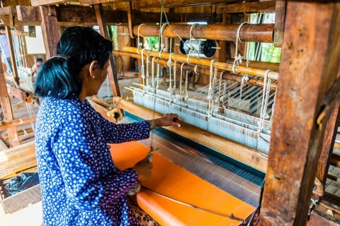 Native woman weaves on a loom