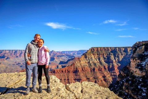 Couple embraces in front of the gigantic gorge of the Grand Canyon
